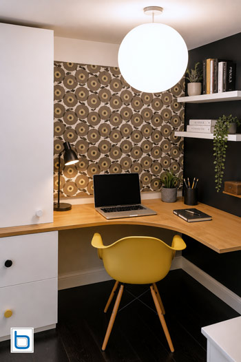 Custom compact home office featuring White built-in cupboards, a curved Oak corner desk, and floating bookshelves tailored to an awkward staircase void.