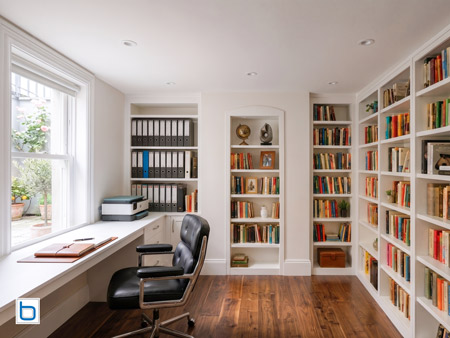 Luxury White built-in cupboards and corner study workstation with extensive floor-to-ceiling library bookcases over a rich hardwood floor.