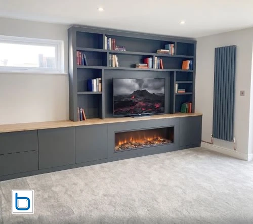 Large custom dark charcoal media wall featuring a central TV recess, linear electric fireplace, open bookshelves, and Oak wood countertops.