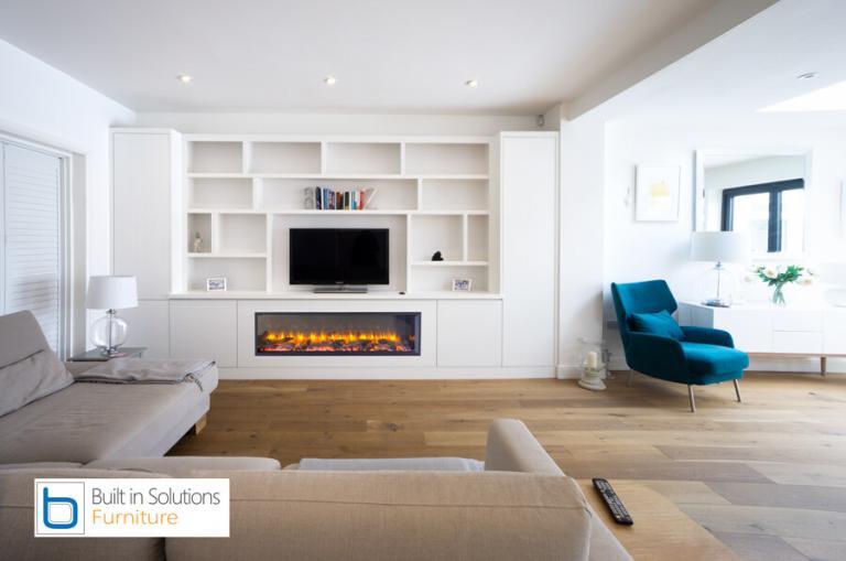 Bespoke White living room furniture showcasing built-in media cupboards, an integrated contemporary electric fireplace, a recessed TV, and open display shelves.