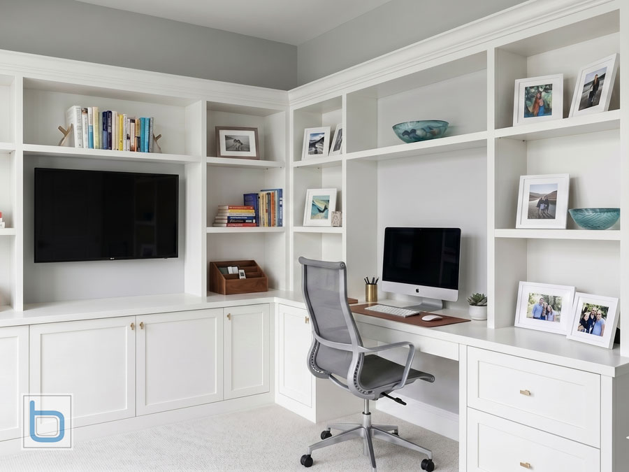 Custom White shaker built-in cupboards and corner study workstation featuring an integrated desk, media unit, and tall open library bookcases.