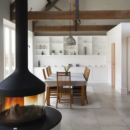 Large fitted cabinets and shelving for a barn conversion living room with full wall bespoke storage and suspended fireplace