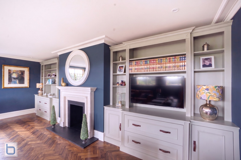 Bespoke Edwardian Style Alcove Cupboards and Fitted Media Unit A sample photo showcasing custom built-in alcove cupboards and a matching media shelving unit painted in a F&B Purbeck Stone colour, featuring detailed Edwardian mouldings, deep drawers, and open bookshelves, with Walnut Herringbone Flooring