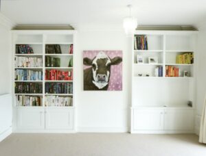 Pair of white painted fitted alcove cupboards with open bookshelves above base cupboards either side of a chimney breast