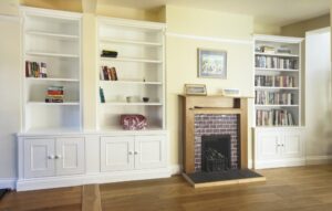 Custom white open bookshelves over low cabinets flanking a brick and natural oak fireplace surround.
