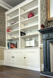 Victorian style fitted alcove cupboards in white with raised panel doors, open shelving above, either side of a period fireplace