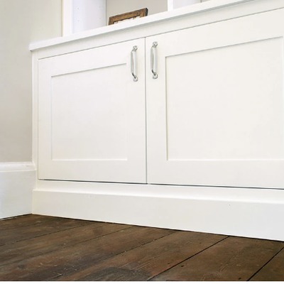 Close-up of a fitted window seat bench with white shaker panel doors and chrome bar handles, built into an alcove beneath a window.