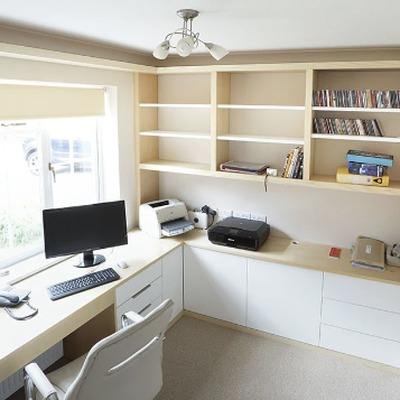 Ash wood and White Cream fitted L shaped desk beside a window, with open shelving above holding books and a printer station built into the cabinetry below.