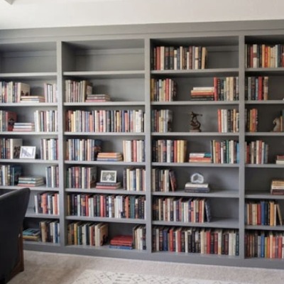 Fitted bookcases painted in charcoal grey with open shelving, filled with books and photo frames, in a living room.