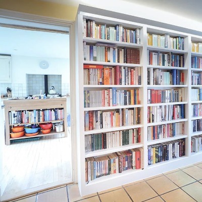 Fitted bookcases lining a hallway wall, leading through to an open plan kitchen with a central island.