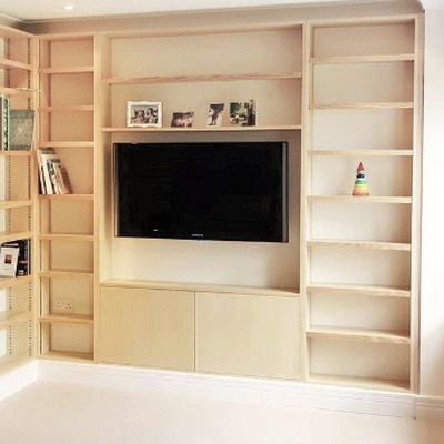 Natural oak fitted media unit with open shelving either side of a wall mounted television and closed base cupboards below.