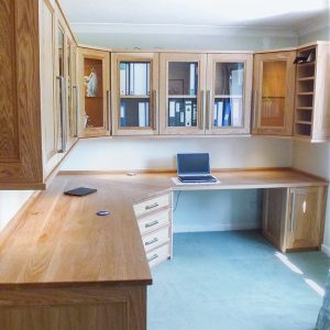Bespoke fitted home office in oak with large L-shaped desk, glazed overhead cabinets and full perimeter storage