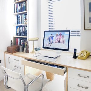 Fitted home office in ash wood with wide desk surface, pull-out drawer storage and floor-to-ceiling bookshelves