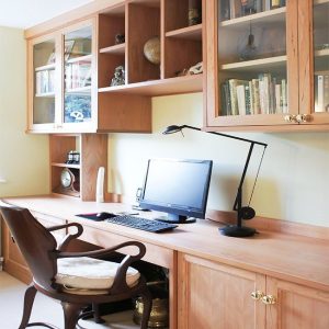 Bespoke fitted home office in cherry wood with floor-to-ceiling shelving, integrated desk and overhead storage