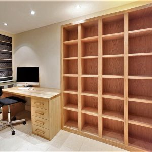 Natural oak fitted home office with floor-to-ceiling open shelving, integrated desk and base drawers, warm timber finish