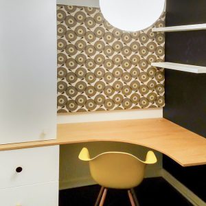 Small contemporary fitted home office desk in oak with single drawer unit, bold patterned wallpaper behind