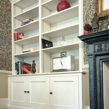 Victorian style fitted alcove cupboards in white with raised panel doors, open shelving above, either side of a period fireplace