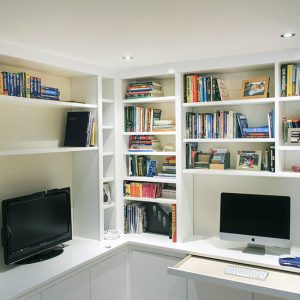 Contemporary fitted home office with L-shaped desk, floor-to-ceiling bookshelves and integrated television recess